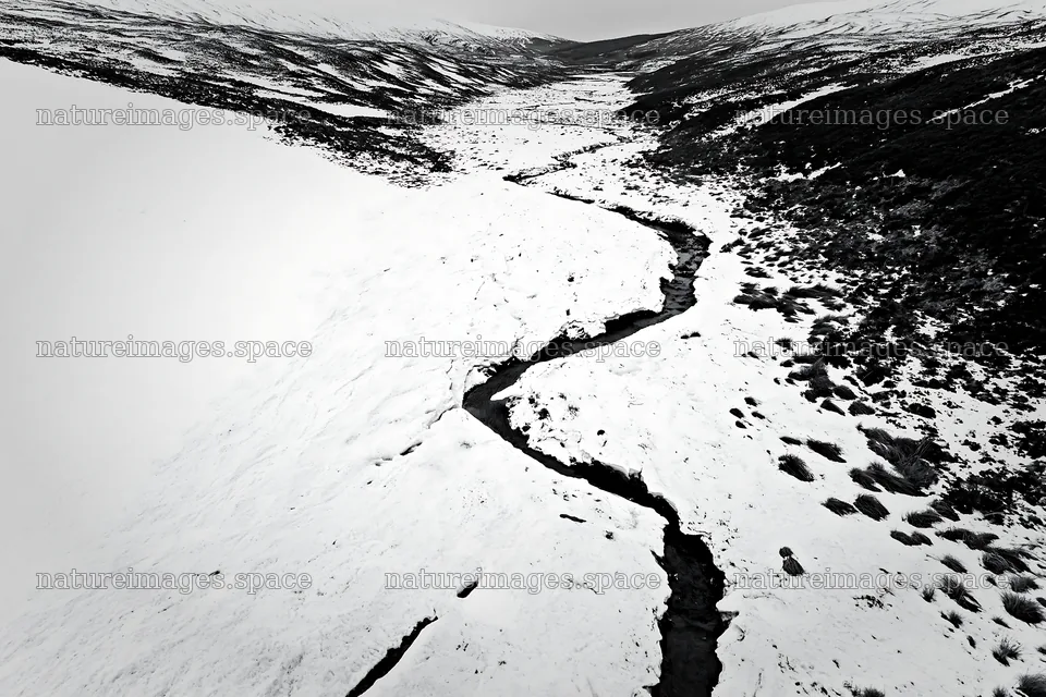 Snowy meadow valley with winding river in aerial view – nature images 9722x6480