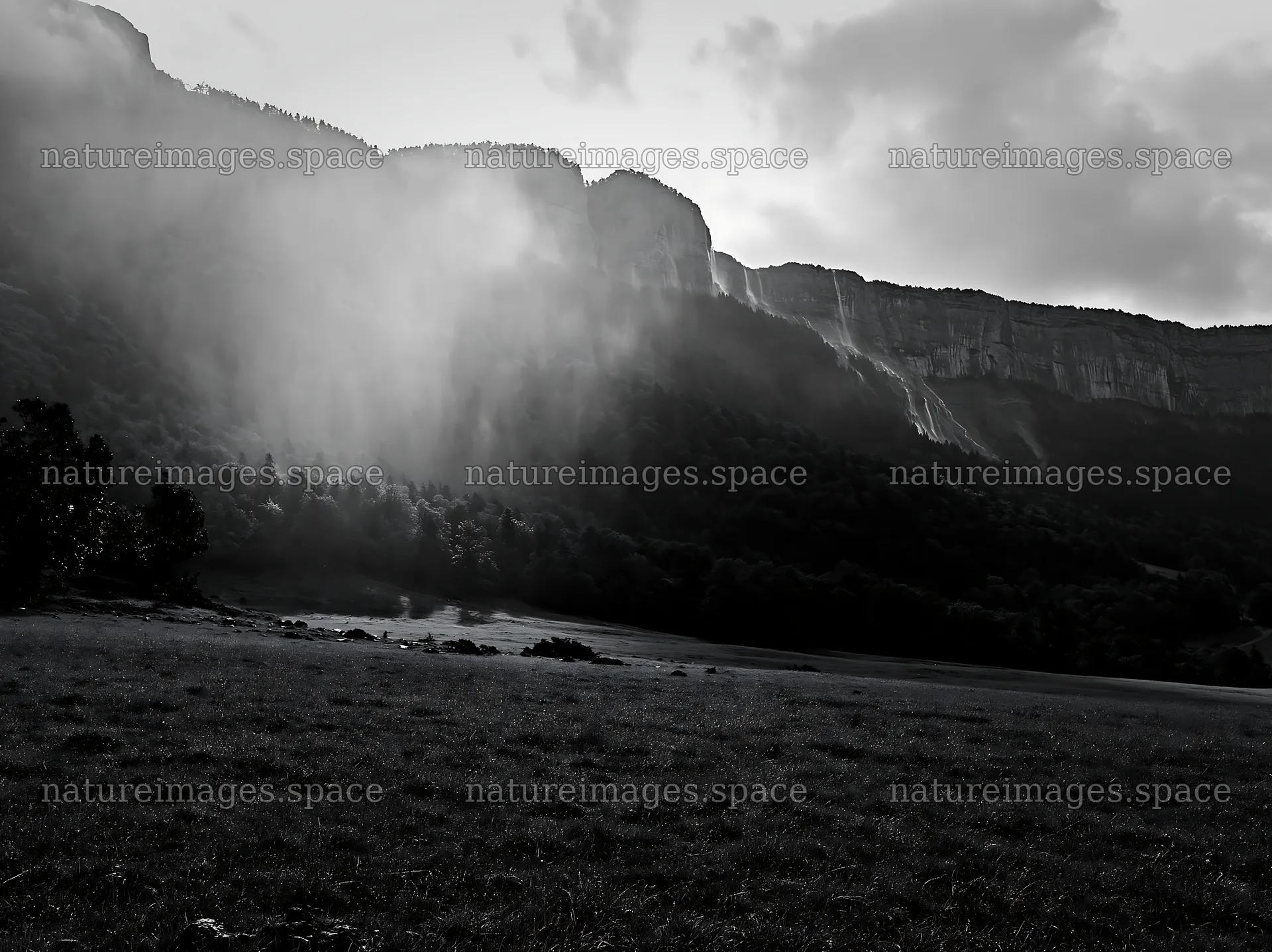 Meadow beneath crags with fog and distant waterfalls – nature images 9174x6866