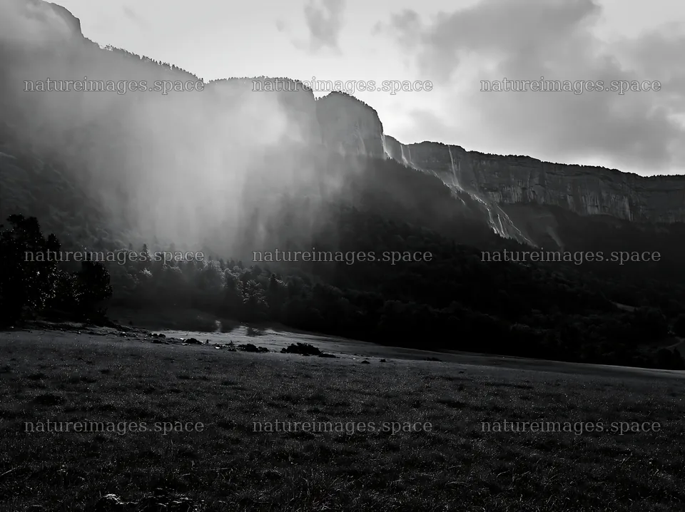 Meadow beneath crags with fog and distant waterfalls – nature images 9174x6866